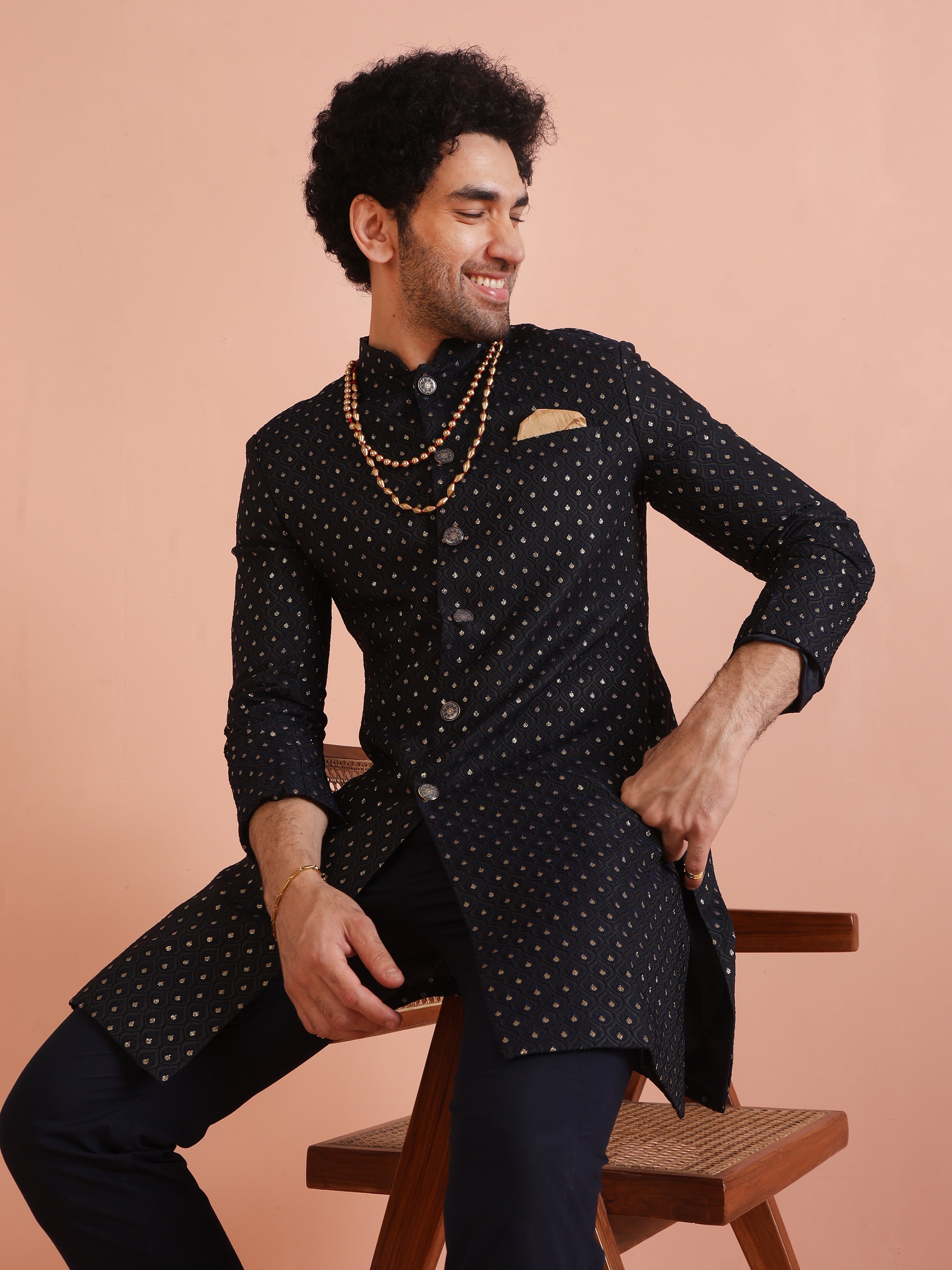The man is sitting on a chair, posing with Navy Blue Embellished Indowestern Set