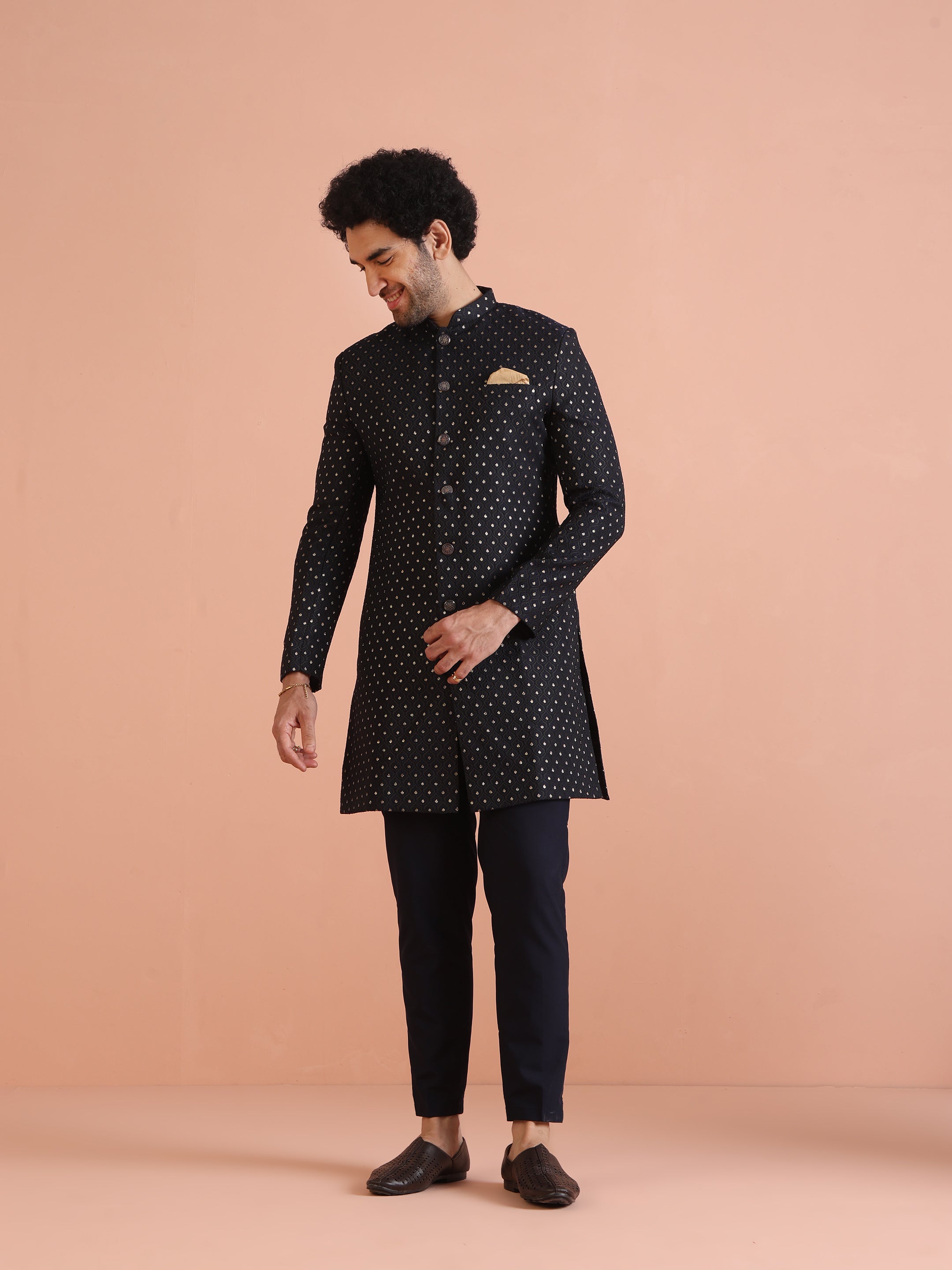 The man is looking downward, posing with Men Navy Blue Embellished Indowestern Trouser Set