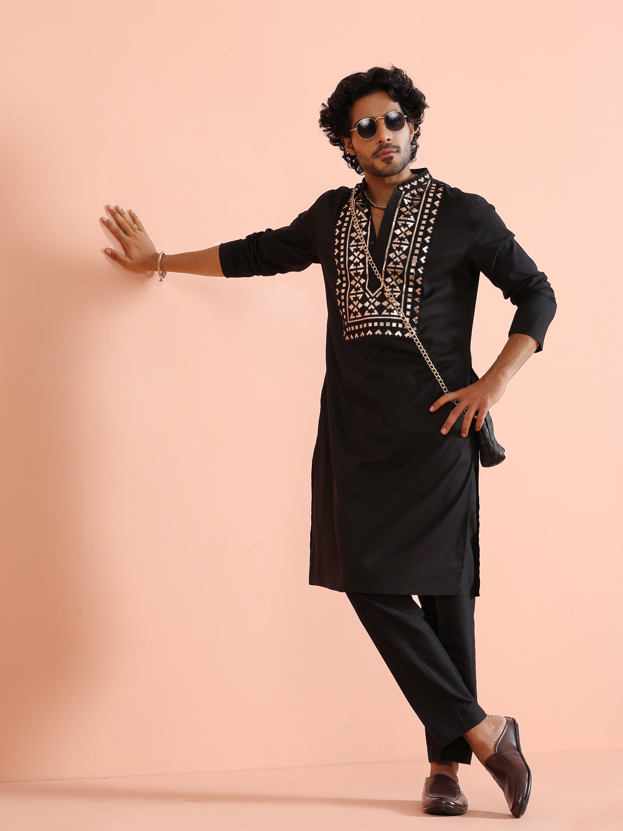 The man in Black Metallic Embroidered Kurta Set is posing stylishly with a crossbag and sunglass